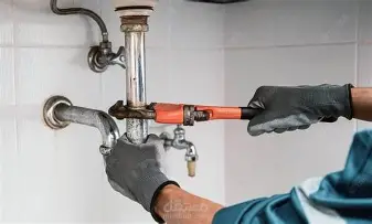 فني سباكة يصلح أنابيب المياه